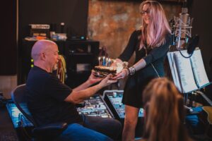 Photo of Taylor Ramone handing Jim Morris a birthday cake with lit candles