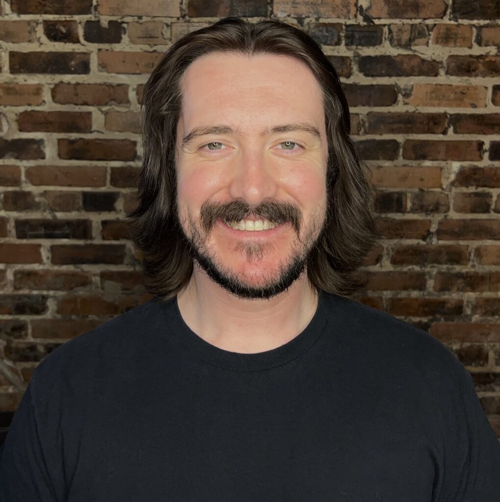 Man in front of brick background.