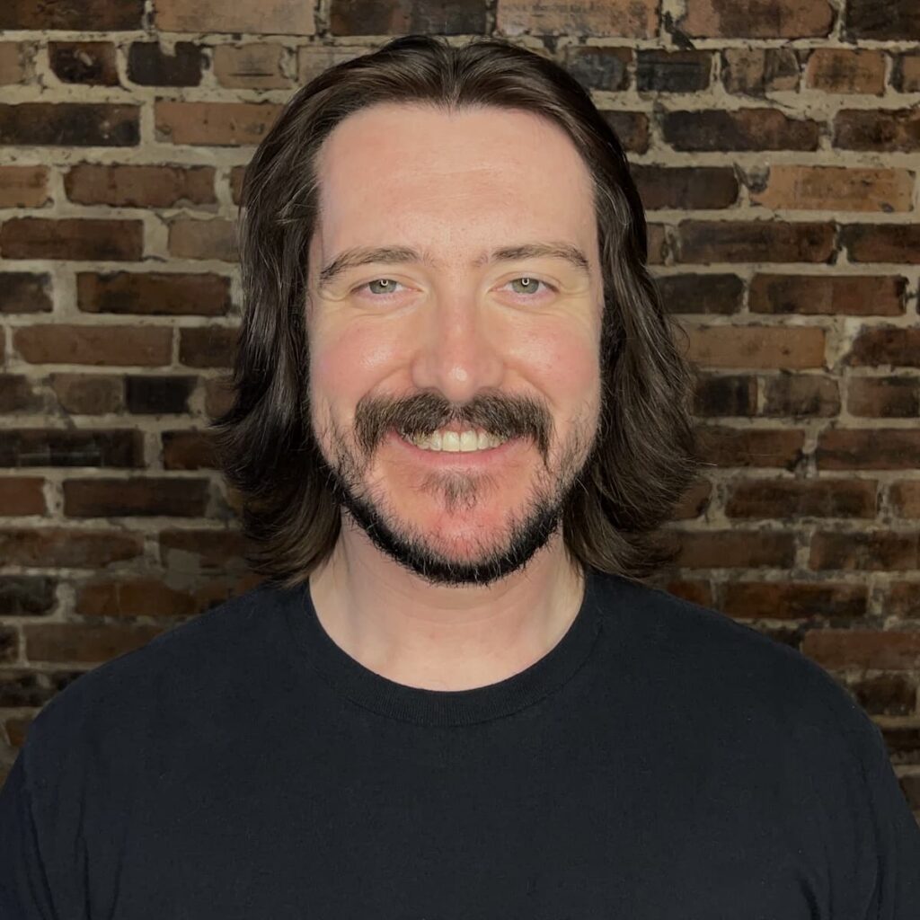 Man in front of brick background.